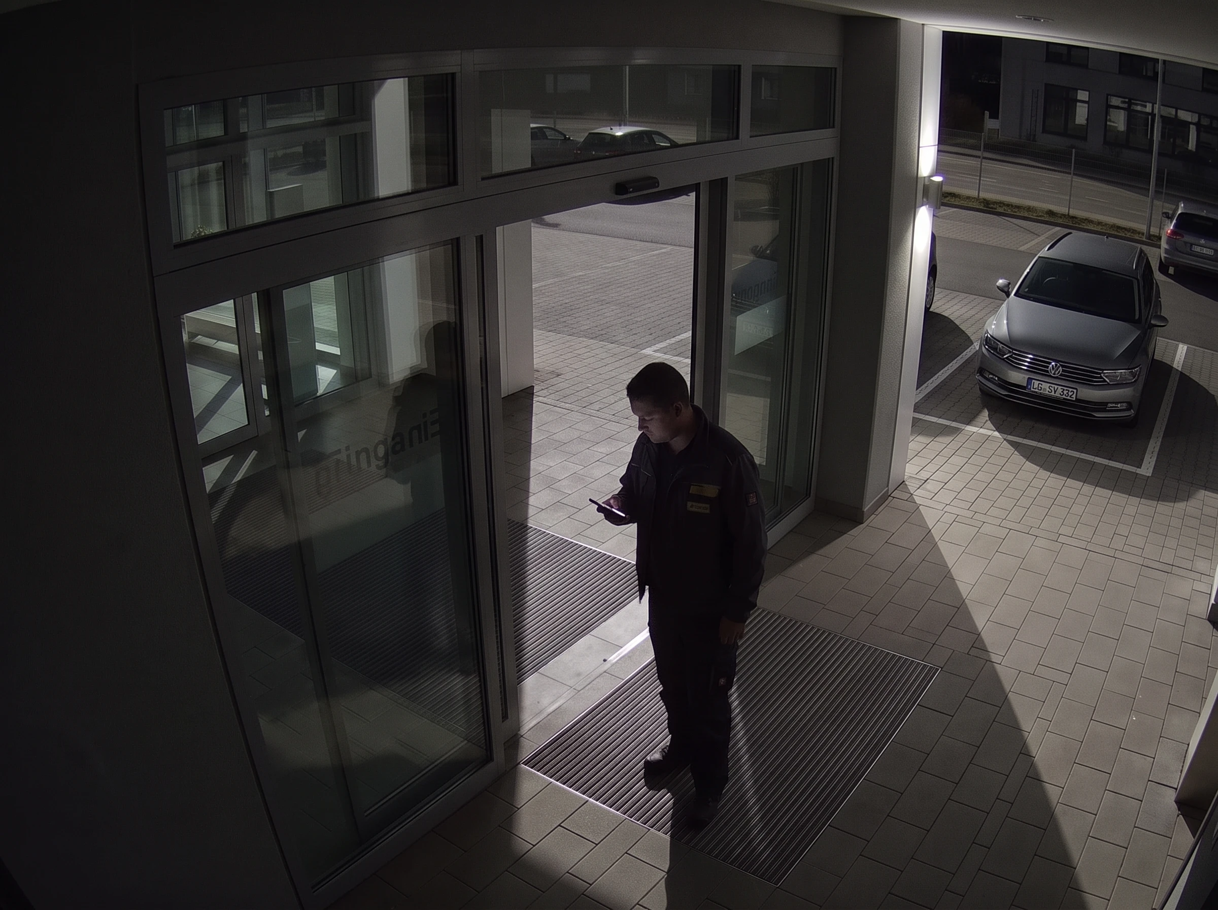 Derselbe Gewerbeeingang bei Nacht mit erkennbarer Person und erkennbarem Fahrzeug